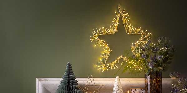 Christmas lights in star shape hung on wall over a wooden sidebaord.
